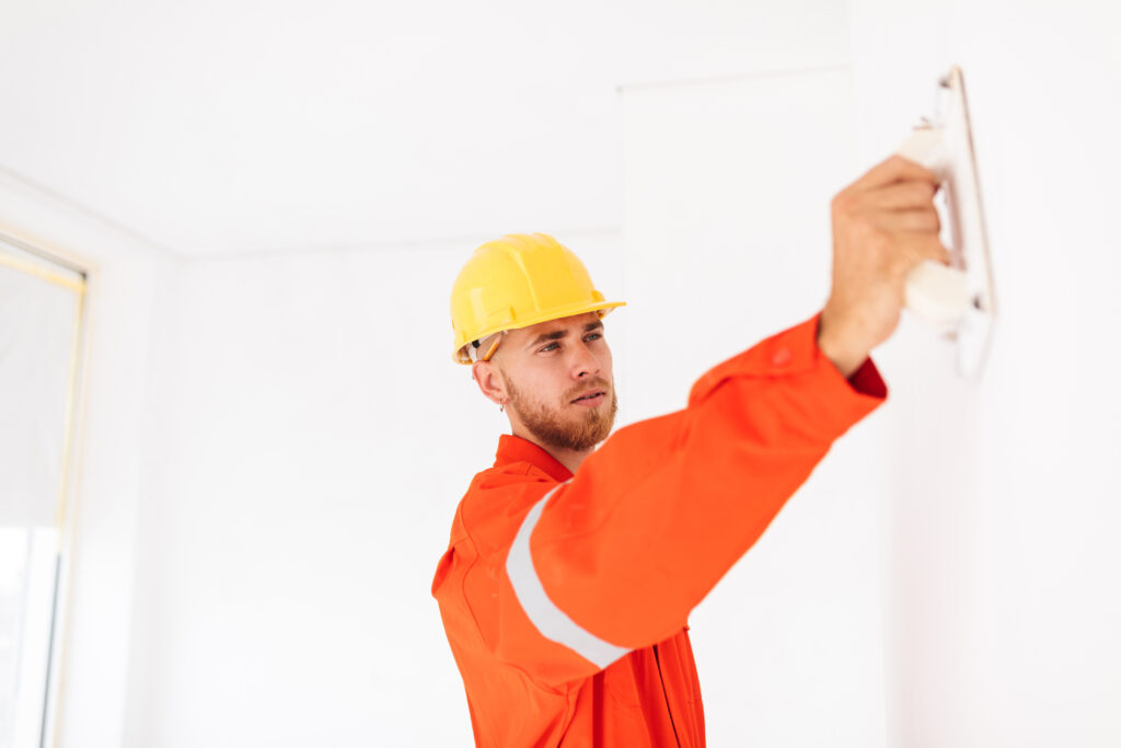 Worker sanding drywall during finishing process in Chilliwack home renovation
