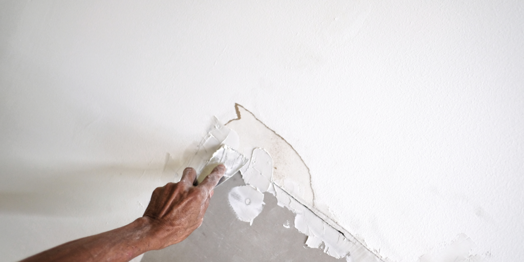 Close-up of a worker repairing damaged drywall with joint compound during drywall repair in Abbotsford
